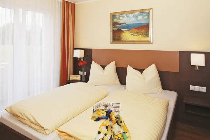 Doppelbett in modernem Hotelzimmer mit Bild an der Wand.