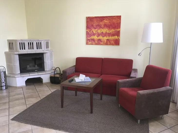 Rotes Sofa und Sessel in modernem Wohnzimmer mit Kamin und Kunst an der Wand.