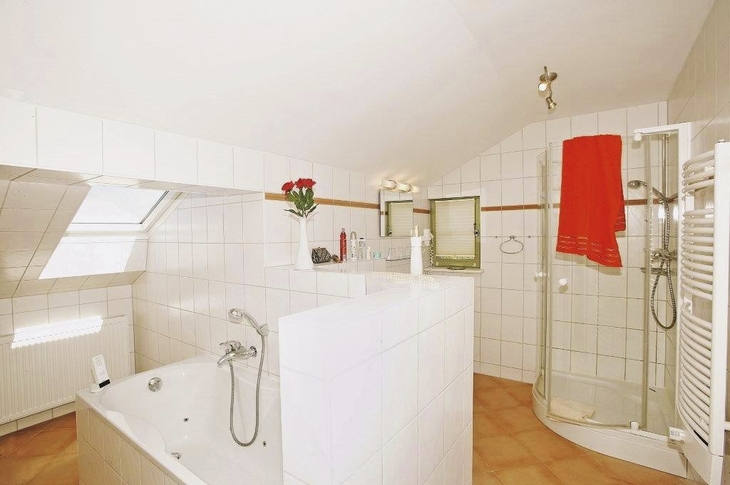 Badezimmer mit Whirlpool, Dusche, roten Handtüchern und weißen Fliesen.