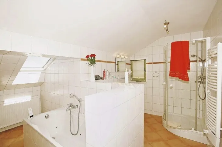 Badezimmer mit Whirlpool, Dusche, roten Handtüchern und weißen Fliesen.