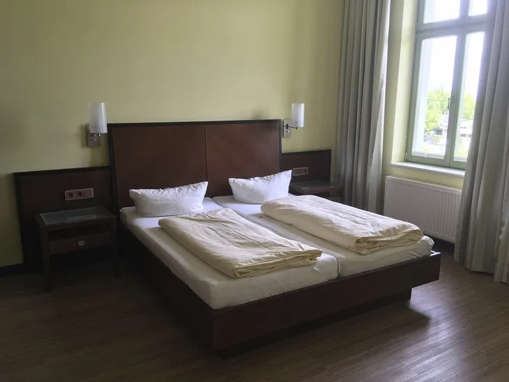 Doppelbett in modernem Schlafzimmer mit Holzboden und großem Fenster.