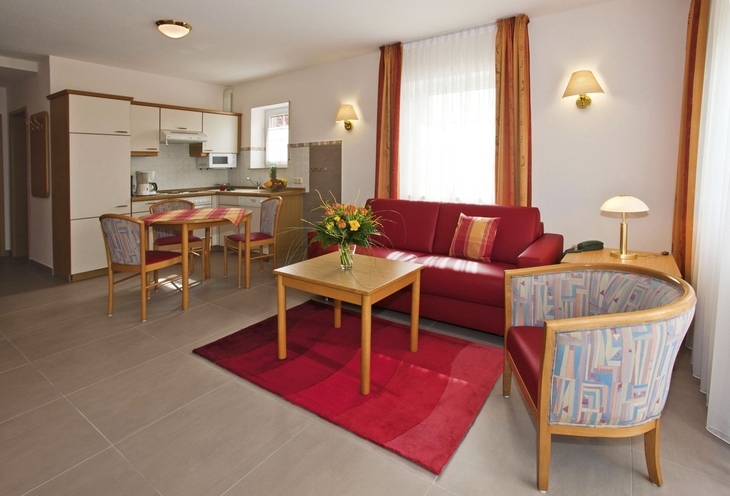 Moderne, gemütliche Wohnzimmerküche mit roten Akzenten und Esstisch.