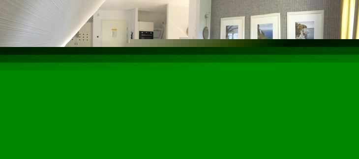 Wohnzimmer einer Ferienwohnung mit Sofa, Esstisch und Kunst an den Wänden.