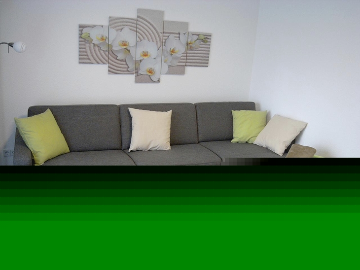 Graues Ecksofa mit Kissen und Couchtisch in modernem Wohnraum.
