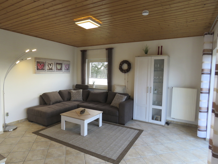 Wohnzimmer mit Ecksofa, Couchtisch und Schrank in einem Ferienhaus.
