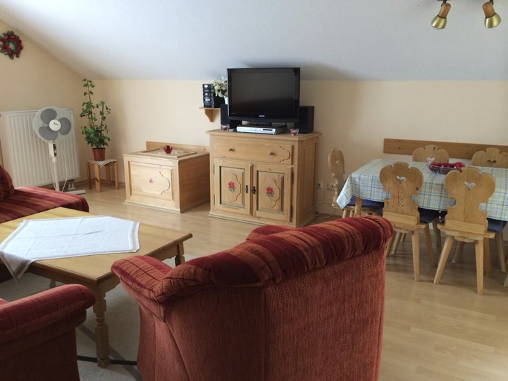 Wohnzimmer mit roten Sofas, TV, Esstisch und heller Holzmöbel.