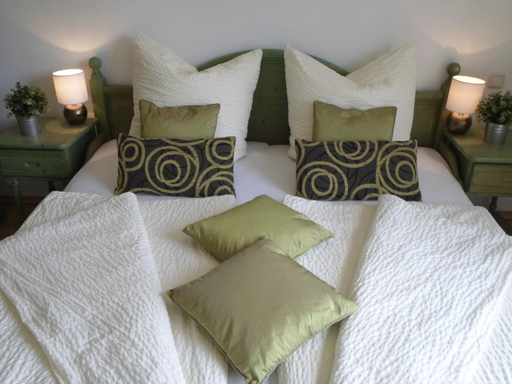 Bett mit grüner Dekoration und weißen Kissen in einem Schlafzimmer.