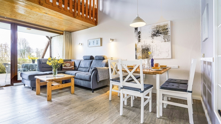 Wohnzimmer in Ferienanlage mit Sofa, Esstisch und Dekorationen