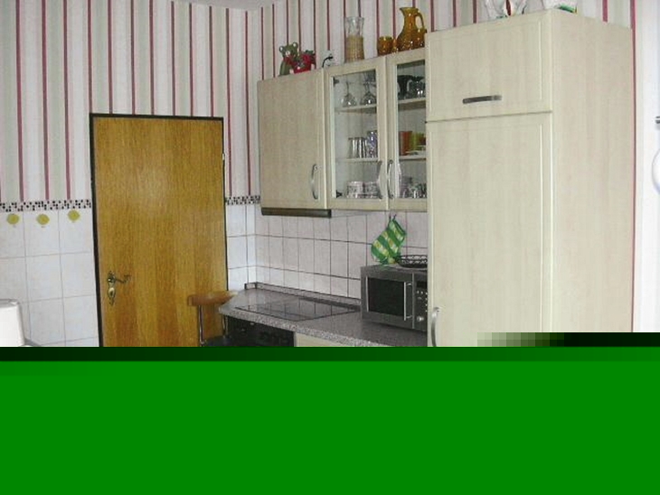Küche mit modernen Schränken, Herd, Mikrowelle und Wandregalen.