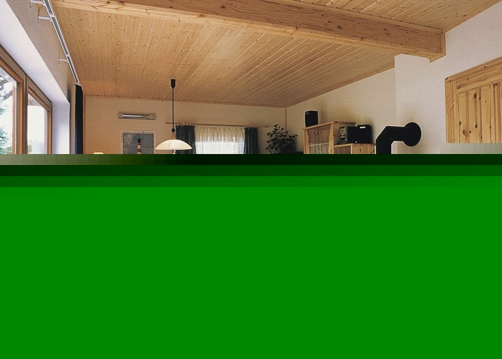 Gemütliches Wohnzimmer mit Holzmöbeln, Esstisch und Kaminofen.
