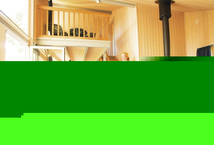 Innenansicht eines Ferienhauses mit Treppe, Ofen und Essbereich.