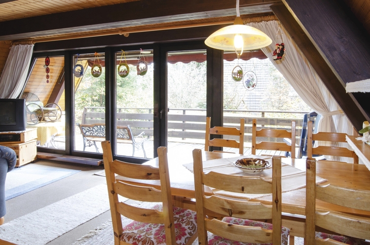 Essbereich in einer gemütlichen Ferienhütte mit Holzstühlen und großem Fenster.