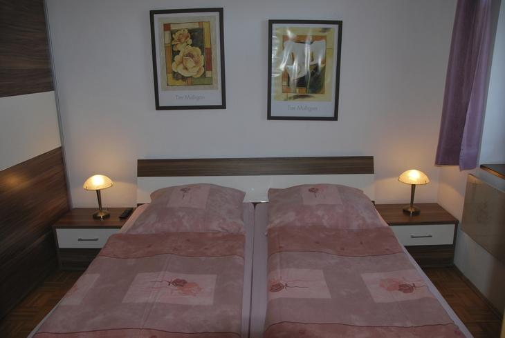 Schlafzimmer mit zwei Einzelbetten und Gemälden an der Wand.