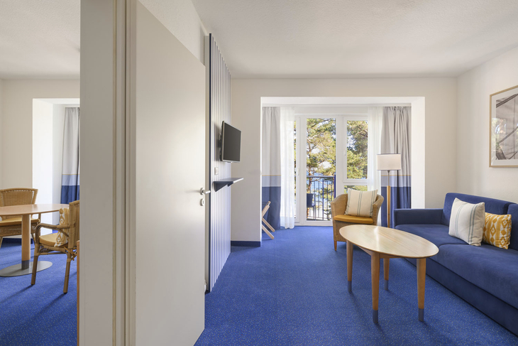 Zweiraum-Ferienwohnung mit Blick auf den Balkon und modernen Möbeln.