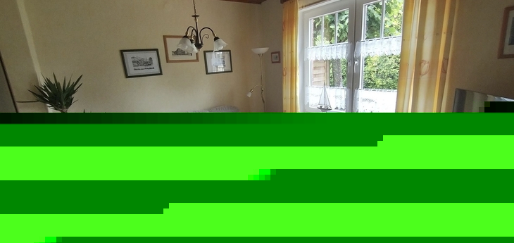 Gemütliches Wohnzimmer mit Sofa, Sesseln, Tisch und Fenstern mit Vorhängen.