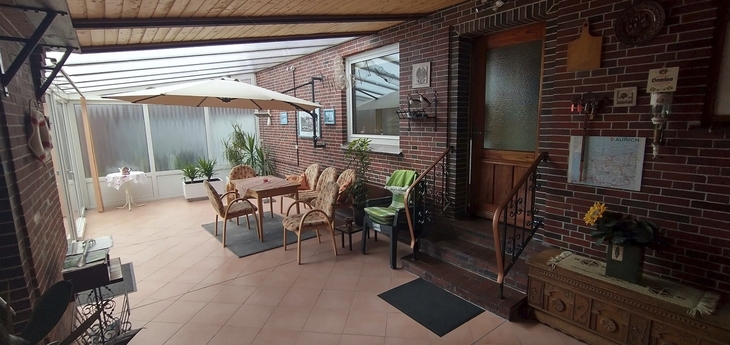 Überdachter Innenhof mit Tisch, Stühlen und Pflanzen.