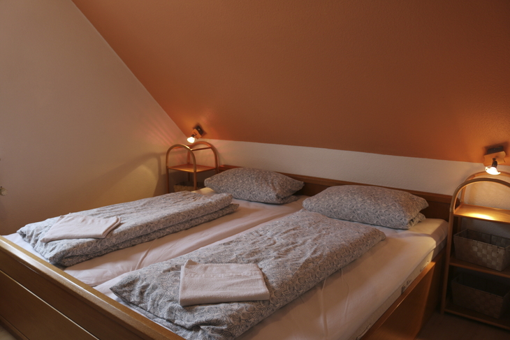 Doppelbett in gemütlichem Ferienwohnungsschlafzimmer mit Dachschräge.