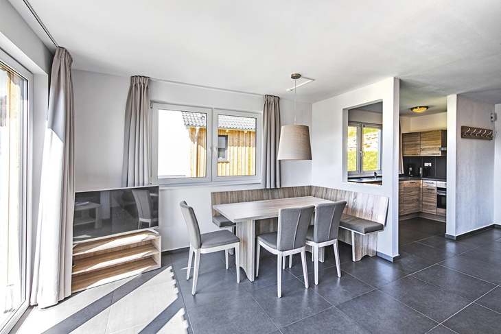 Essbereich in einem modernen Ferienhaus mit Tisch, Stühlen und Blick zur Küche.