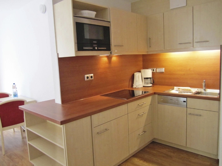 Moderne Küchenzeile mit Holzfronten und Geräten in heller Umgebung.