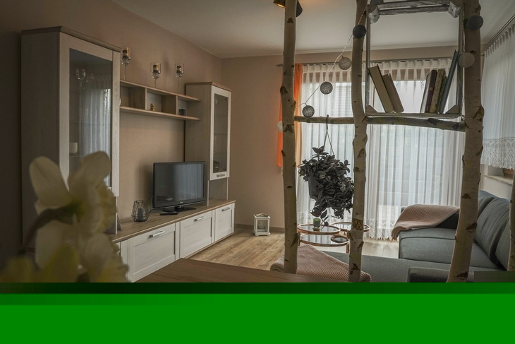 Gemütliches Wohnzimmer mit Sofa, Regal und Fernseher, Blick aus Essbereich.
