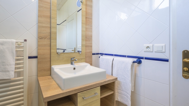 Badezimmer mit Waschbecken, Spiegel und Handtüchern.