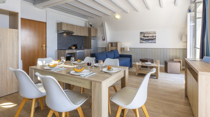Essbereich und Wohnzimmer in einer modernen Ferienwohnung mit Holzmöbeln und Küchenzeile.