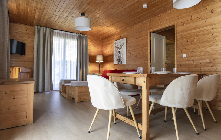Essbereich in einem holzgetäfelten Chalet mit Tisch, Stühlen und Sofa.