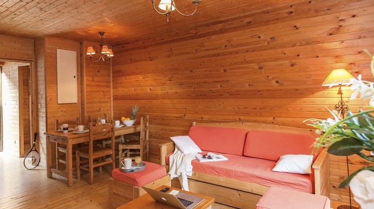 Wohnzimmer mit Holzwänden, Sofa, Esstisch, Lampen und Dekoration.
