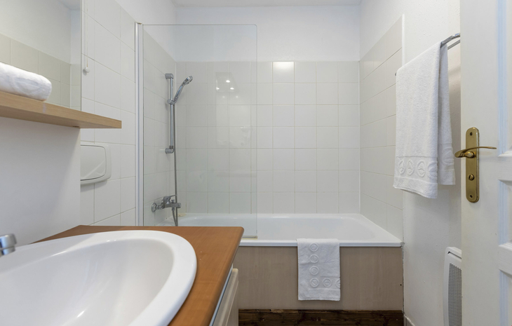 Badezimmer mit Badewanne, Dusche, Waschbecken und Handtüchern.