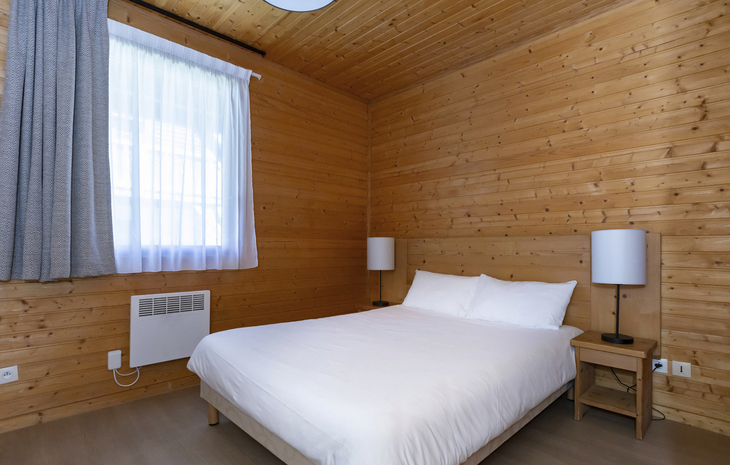 Schlafzimmer in einem Chalet mit Doppelbett und Holzwänden.