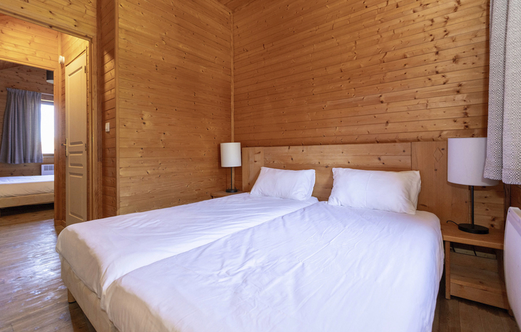 Schlafzimmer in einem Holz-Chalet mit zwei Einzelbetten und Nachttischen.