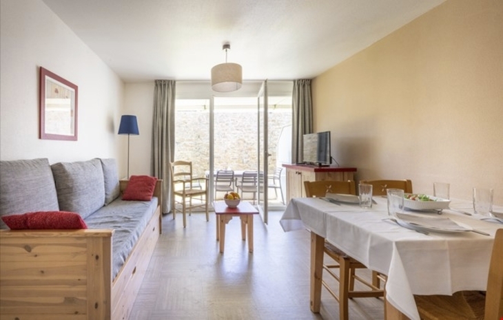 Wohnzimmer mit Sofa, Esstisch und Stühlen in einer Ferienwohnung