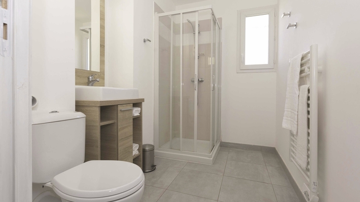 Modernes Badezimmer mit Dusche, WC, Waschbecken und Handtuchhalter.