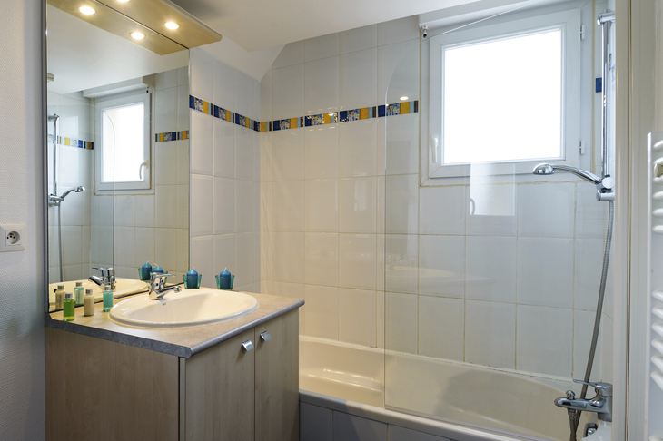 Helles Badezimmer mit Badewanne und Fenster.