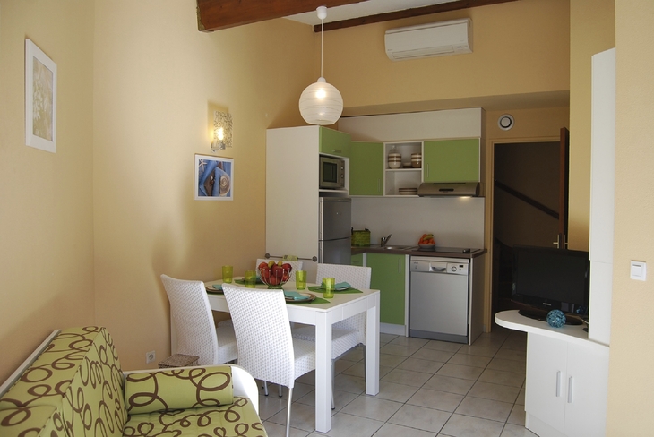 Kleine Küche mit Esstisch und grünen Akzenten in einem Ferienapartment.