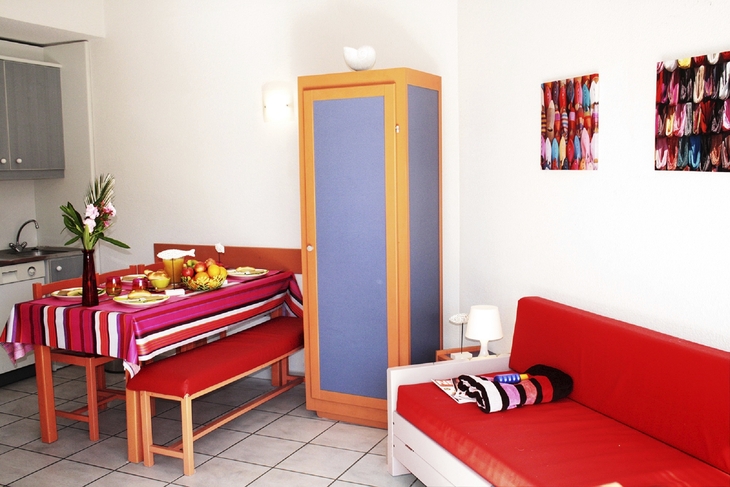 Essbereich in einer Ferienwohnung mit Tisch, Stühlen, rotem Sofa und Dekoration.