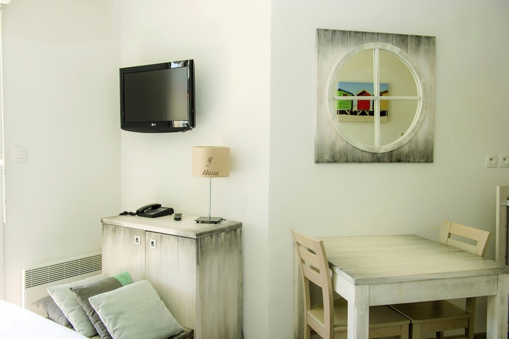 Heller Raum mit Tisch, Stühlen, Wandfernseher und Wanddekoration.