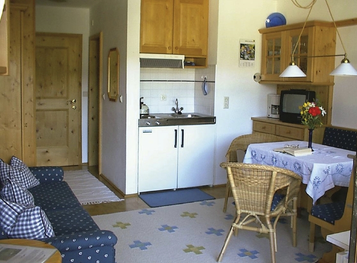 Kleine, gemütliche Küche mit Esstisch und Sofa, Holzschränken und hellem Interieur.