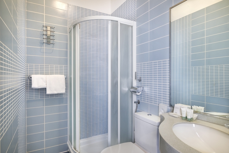 Badezimmer mit blauen Fliesen, Dusche, Waschbecken und Handtuchhalter.