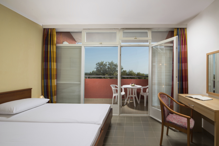 Ein Schlafzimmer mit Doppelbett, Balkon, Tisch und Stuhl im Lanterna Sunny Resort.