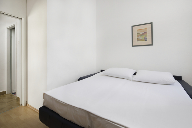 Schlafzimmer mit Doppelbett und Wandbild in Ferienwohnung.