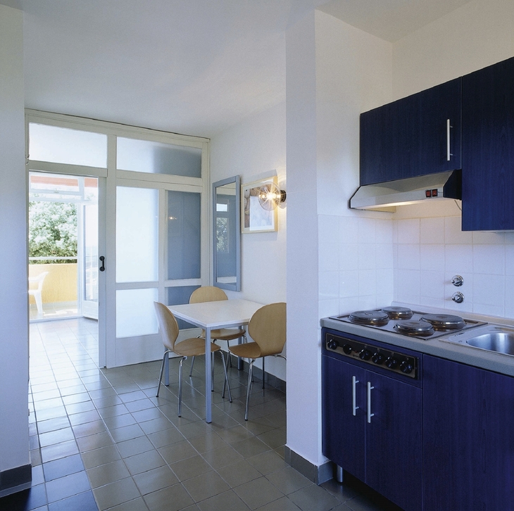 Kleine Küche und Essbereich mit Zugang zum Balkon im Apartment.