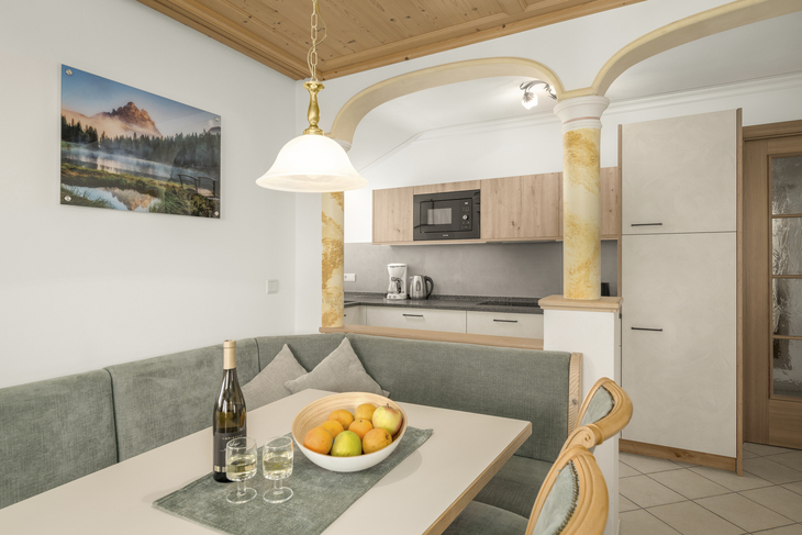 Essbereich mit Tisch, Stühlen, Obstschale und Lampe in einer Wohnungsküche.