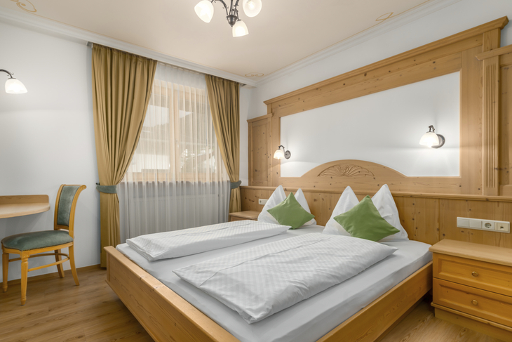 Gemütliches Schlafzimmer mit Doppelbett und Holzmöbeln in einem Hotelzimmer.