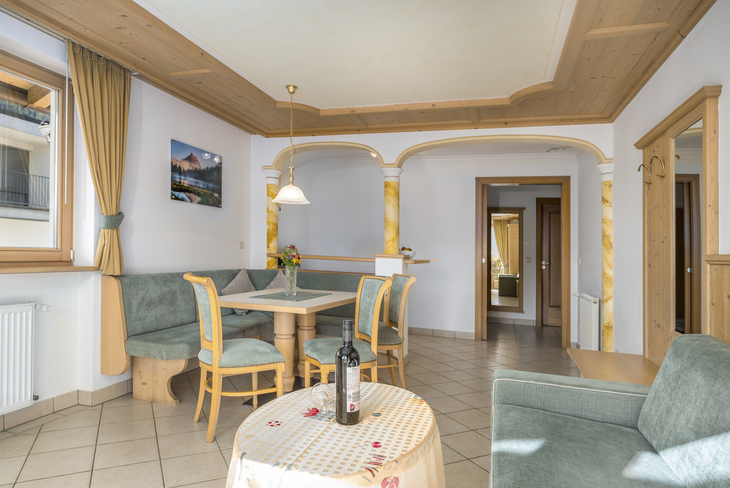Wohnzimmer mit Holzmöbeln, Esstisch, Sofa und Flasche auf Tisch