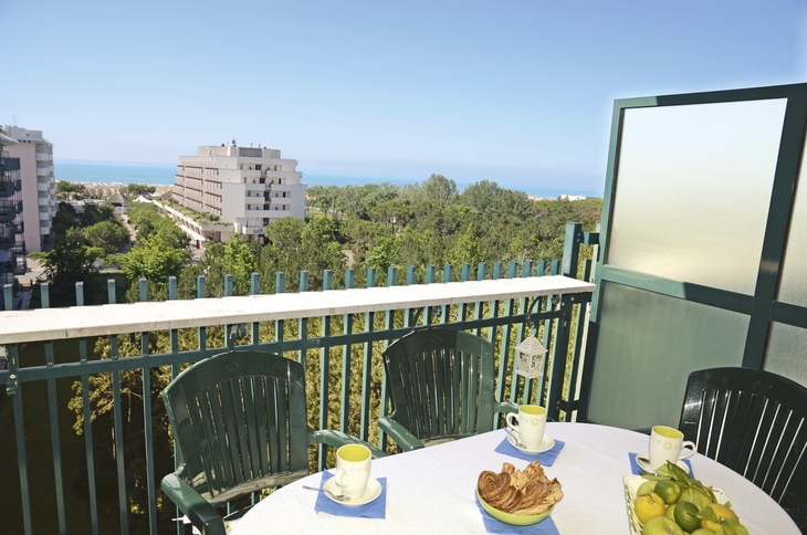 Balkon mit Tischen und Stühlen, Blick auf Gebäude und Meer in Bibione.