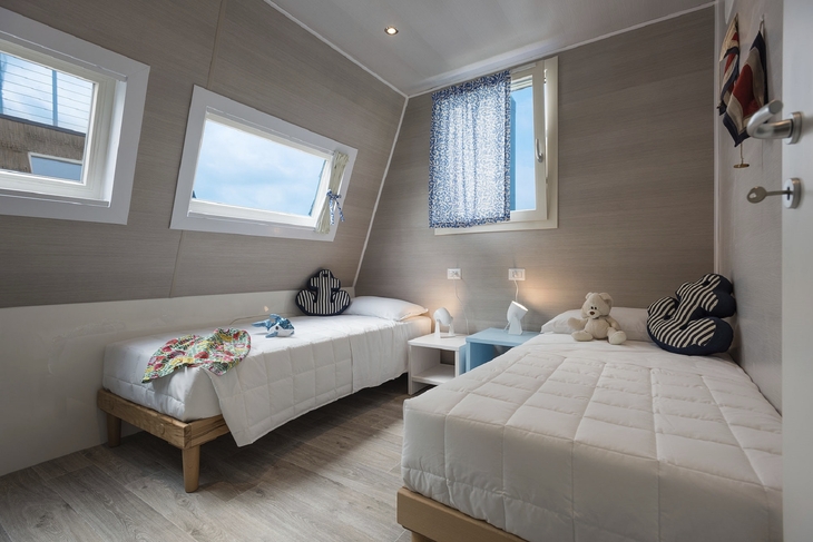 Zwei Einzelbetten in einem hellen, modernen Zimmer mit blauen Akzenten.