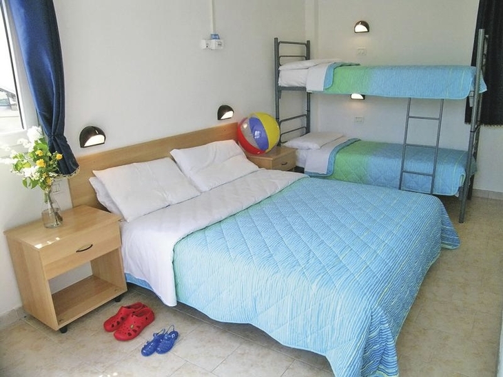 Doppelbett und Etagenbett in hellem Apartment mit blauen Akzenten.