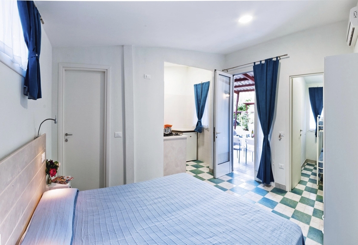 Komfortabler Bungalow mit Bett, Vorhängen und Zugang zur Terrasse.