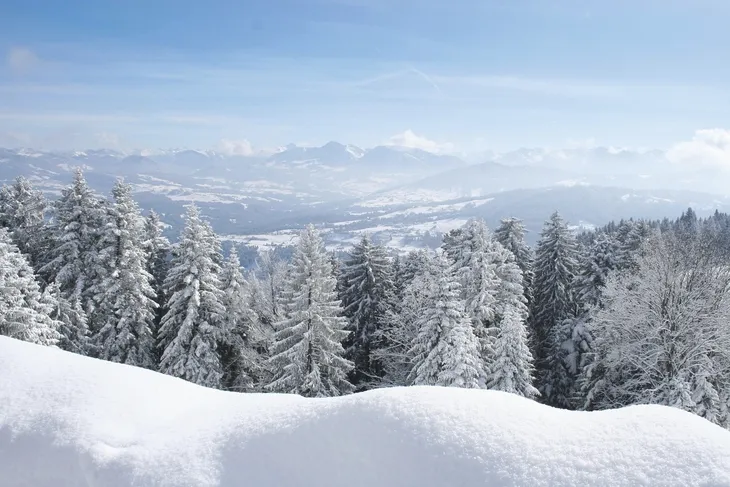 Verschneite Landschaft mit Bergen und Bäumen im Winter.